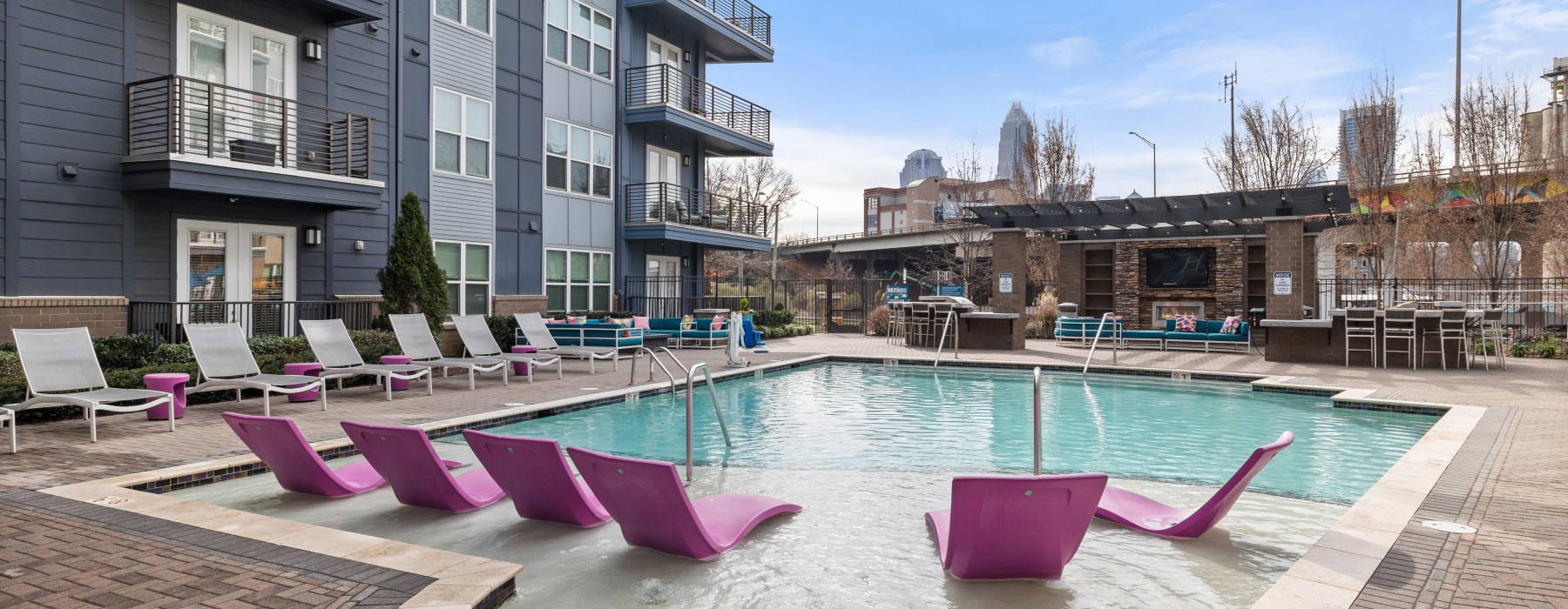 Pink loungers in pool area with city skyline