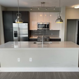 Live at Cadence Music Factory Gray kitchen island with sink in front of stainless steel appliances and cabinets at Cadence Music Factory apartments in Uptown Charlotte, NC.